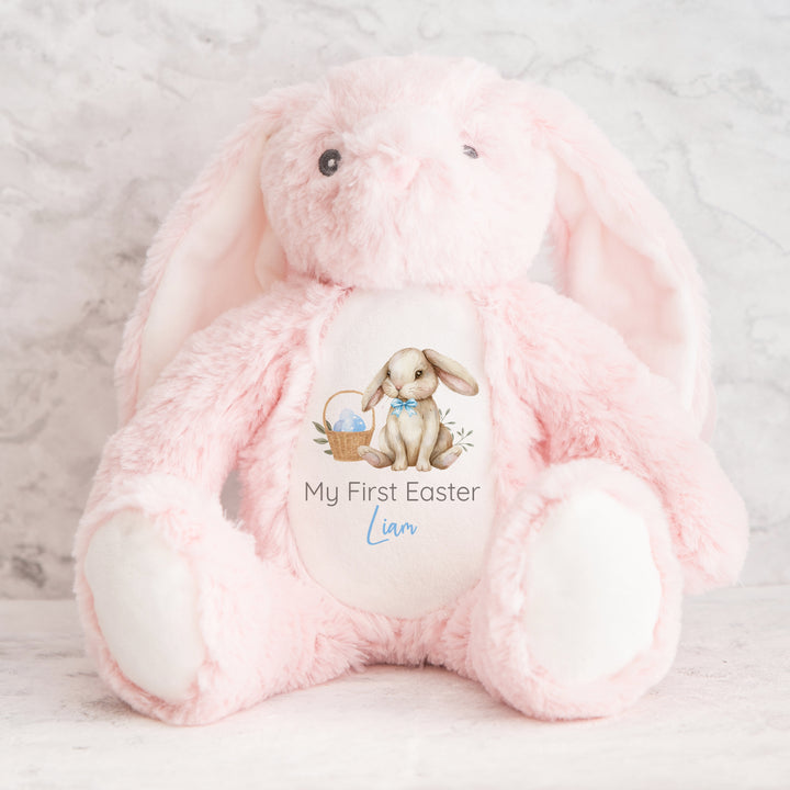 Personalised pink bunny Easter teddy that says 'My First Easter Liam'. This design features a brown bunny wearing a bow tie next to an Easter basket full of blue Easter eggs