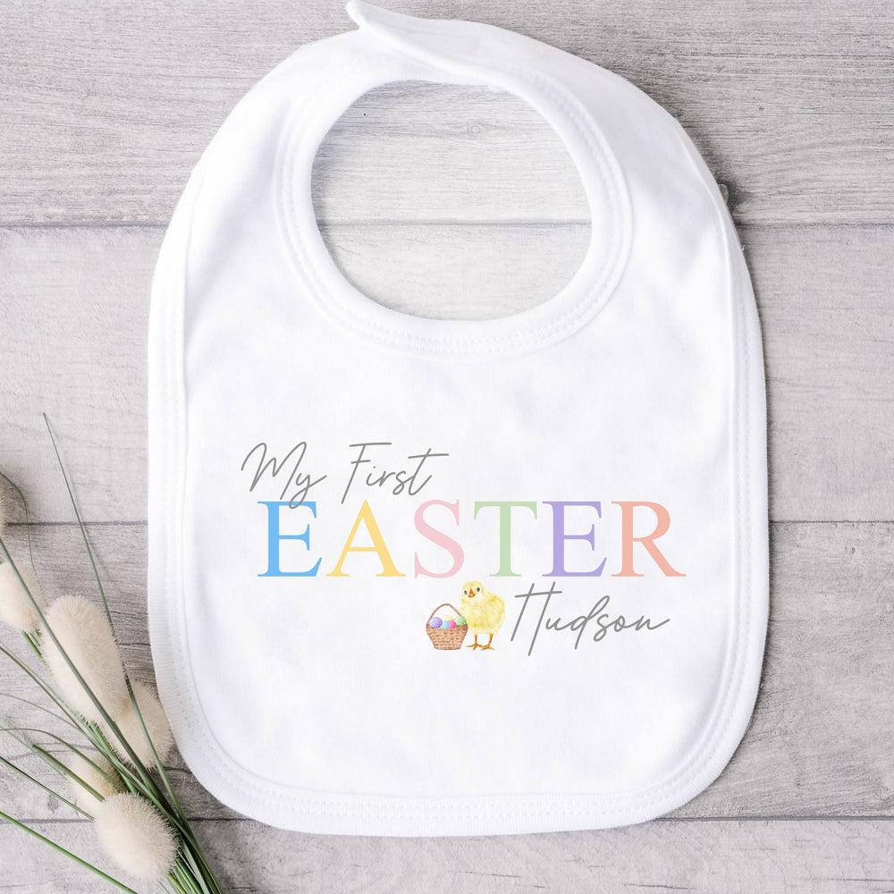 Personalised white Easter baby bib that says 'My First Easter Hudson'. This design features a yellow chick