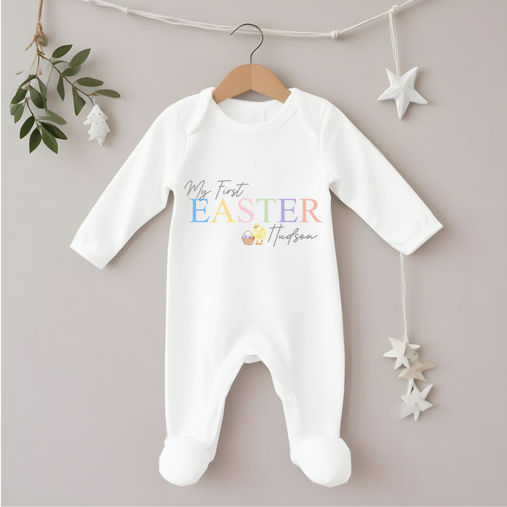 Personalised white Easter baby grow/sleepsuit that says 'My First Easter Hudson'. This design features a yellow chick