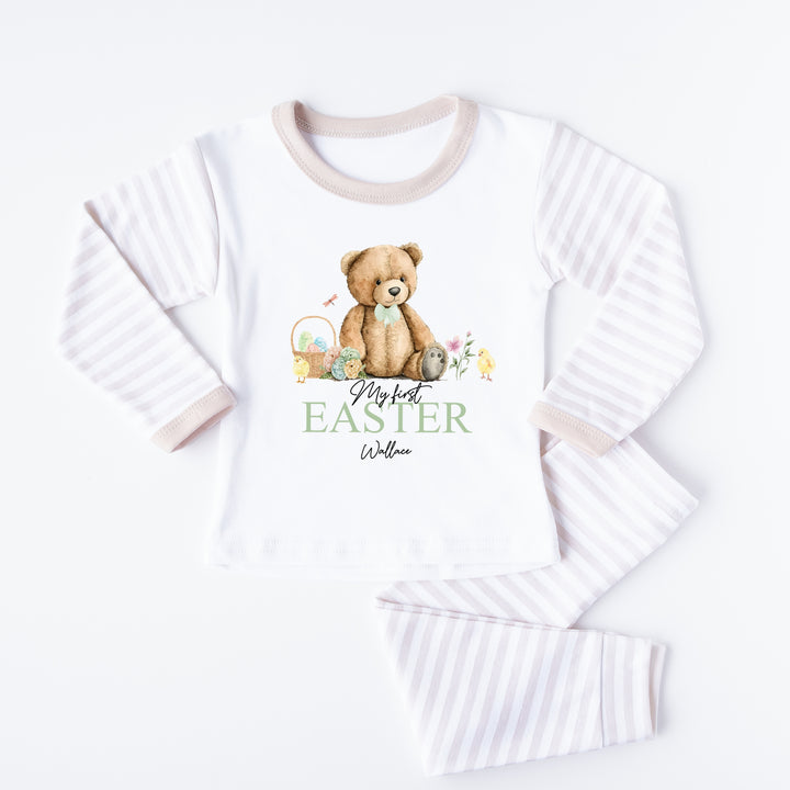 Personalised beige stripe Easter pyjamas that say 'My first EASTER Wallace'. This design features a teddy bear wearing a sage green bow tie surrounded by Easter eggs