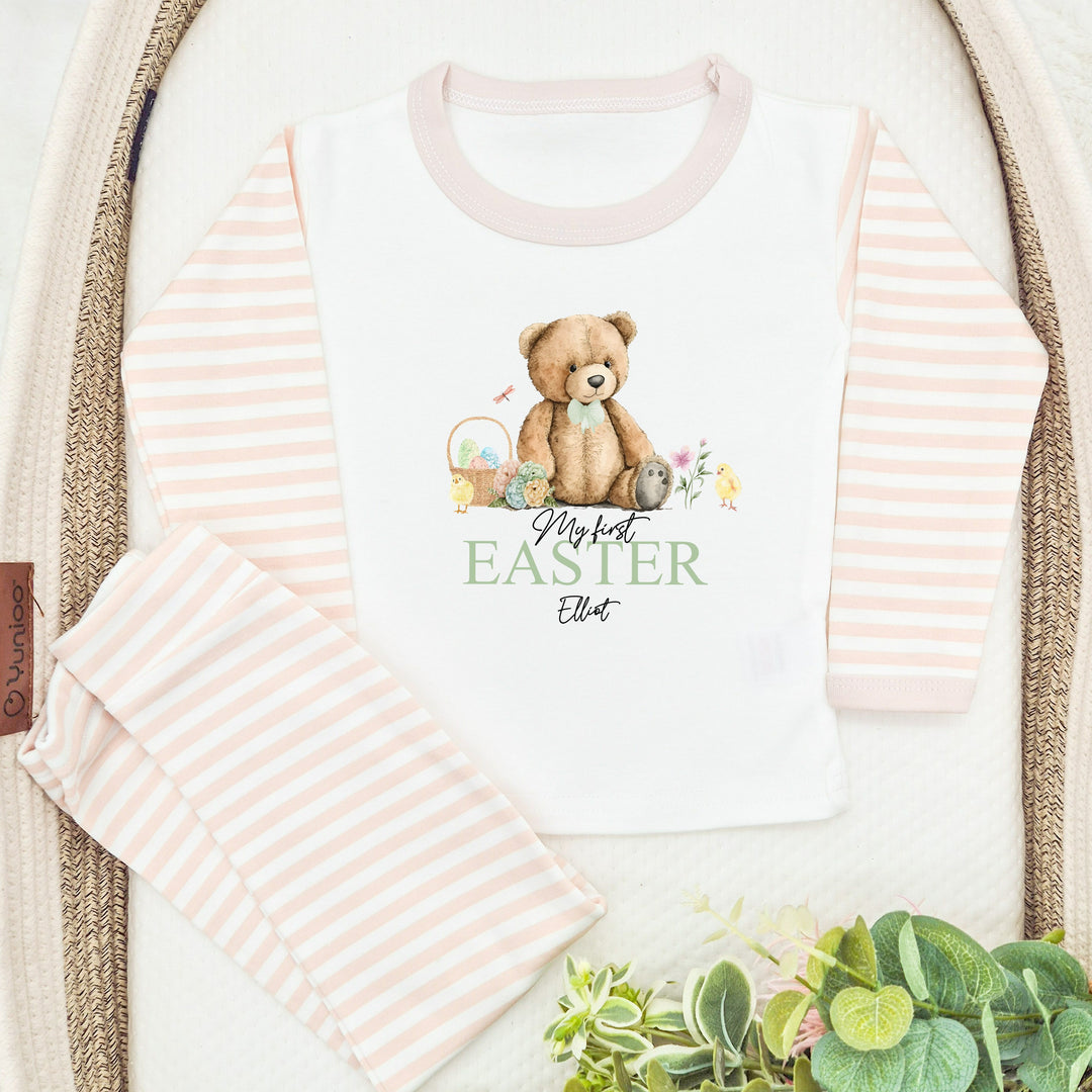 Personalised beige stripe Easter pyjamas that say 'My first EASTER Elliot'. This design features a teddy bear wearing a sage green bow tie surrounded by Easter eggs