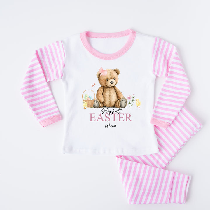 Peronalised pink stripe Easter pyjamas that say 'My First Easter Winnie'. This design features a teddy wearing a pink bow surrounded by an easter basket