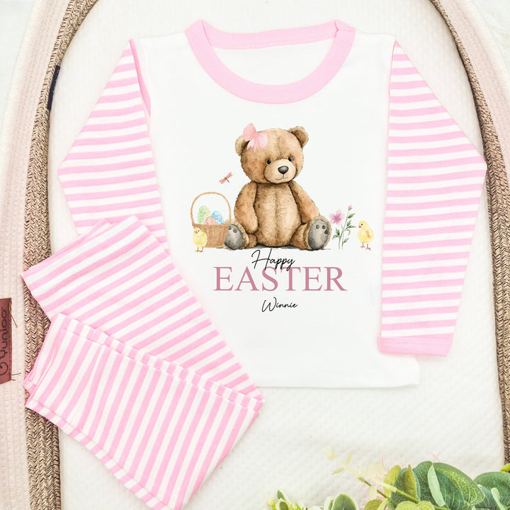 Peronalised pink stripe Easter pyjamas that say 'Happy Easter Winnie'. This design features a teddy wearing a pink bow surrounded by an easter basket