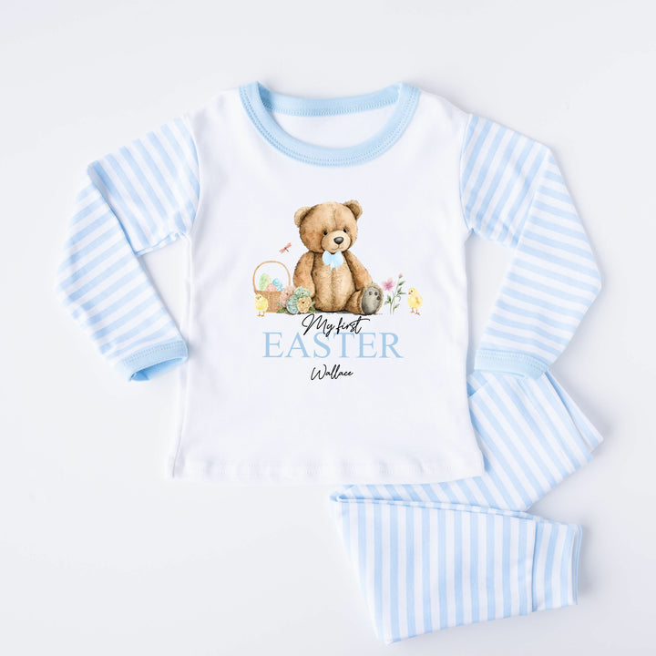 Personalised blue stripe Easter pyjamas saying 'My First Easter Wallace'. This design features a teddy wearing a blue bow tie sitting next to an easter egg basket