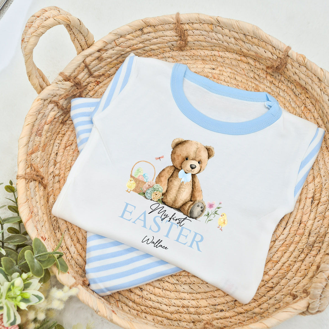 Personalised blue stripe Easter pyjamas saying 'My First Easter Wallace'. This design features a teddy wearing a blue bow tie sitting next to an easter egg basket