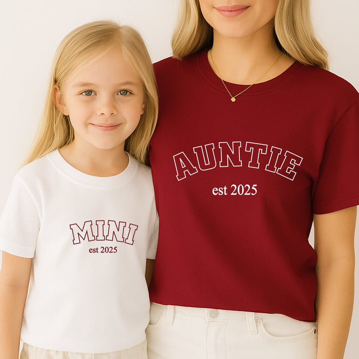 Two people wearing shirts with 'MINI est 2025' and 'AUNTIE est 2025' text.