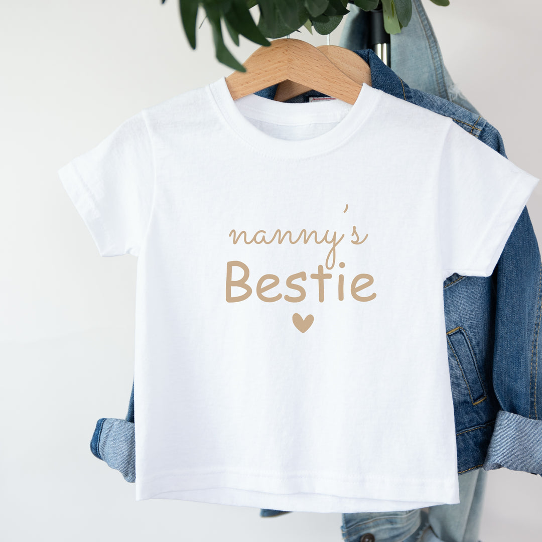 White t-shirt with 'nanny's Bestie' text on a hanger with denim jacket