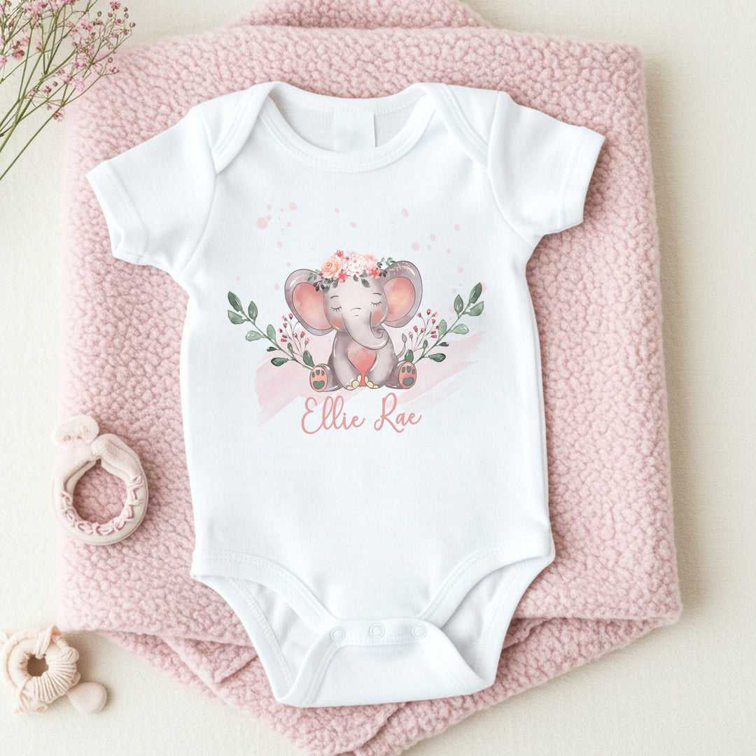 a personalised white baby vest that says 'Ellie Rae'. This design features an elephant wearing a flower crown