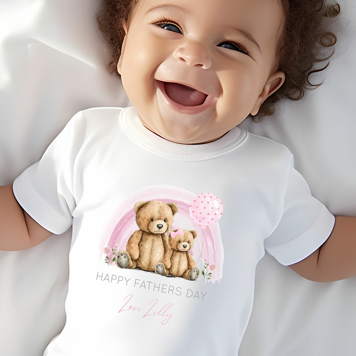 Personalised white Father's Day baby vest that says 'Happy Fathers Day Love Lilly'. This design features a pink rainbow with 2 teddy bears sitting in the middle of it 