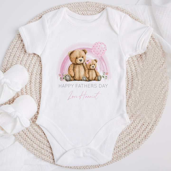 Personalised white Father's Day baby vest that says 'Happy Fathers Day Love Harriet'. This design features a pink rainbow with 2 teddy bears sitting in the middle of it 