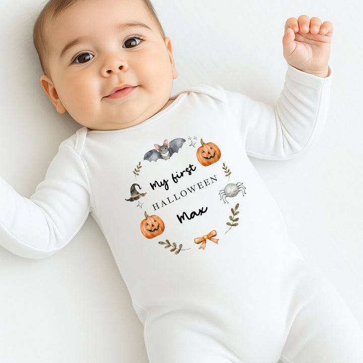 Baby wearing a Halloween-themed onesie with pumpkins and text on a white background