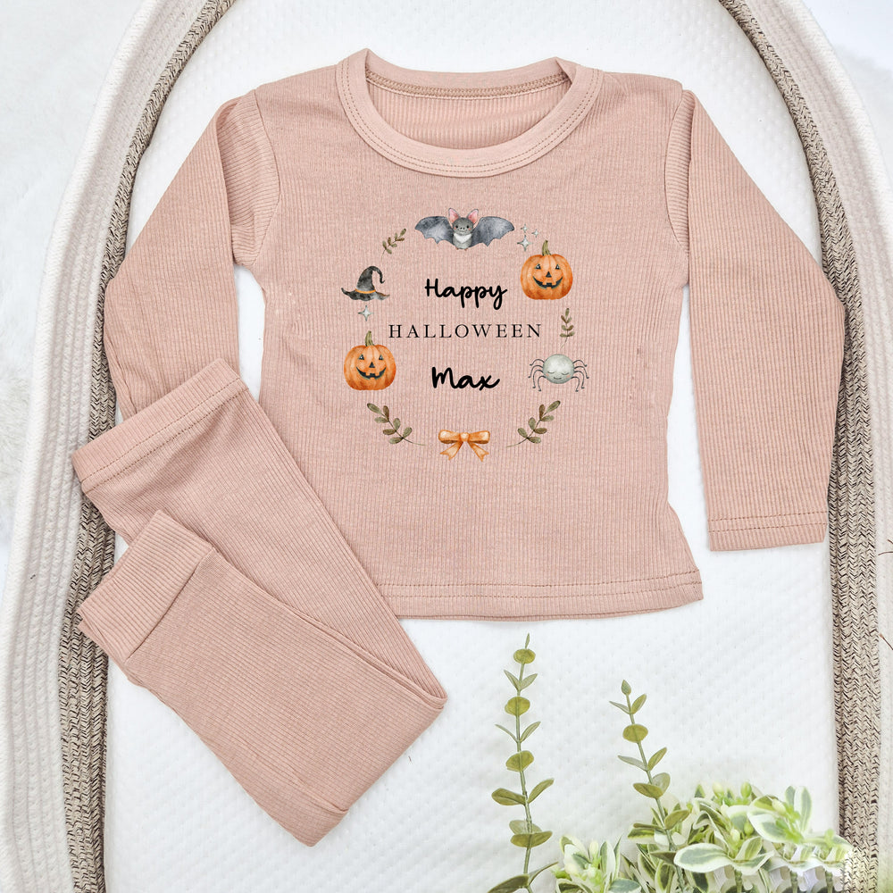 Pink Halloween-themed children's outfit with pumpkins, bats, and text on a white background.