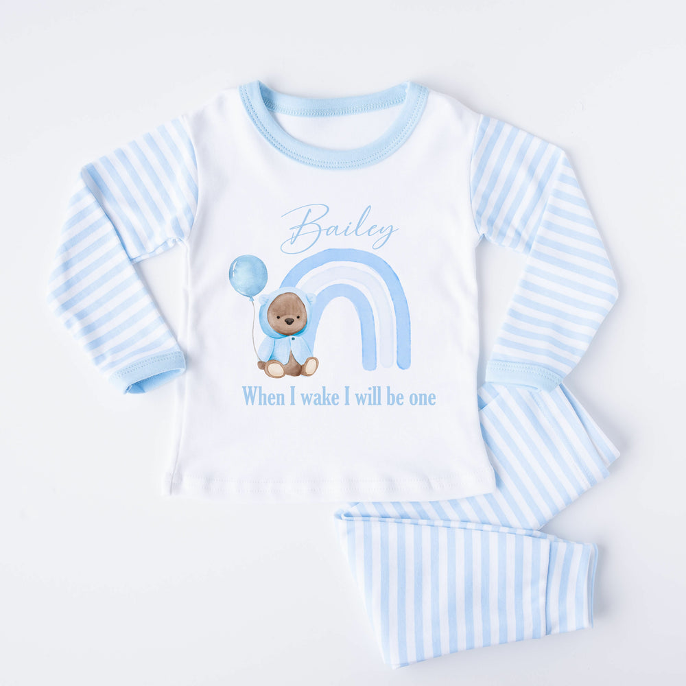 Blue Stripe birthday pyjamas that say 'Bailey When I Wake I will be one'. This design features a blue rainbow and a teddy bear wearing a blue jacket holding a balloon