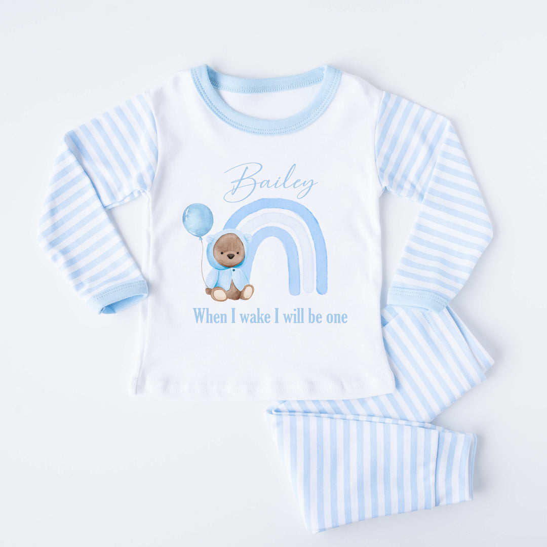 Blue Stripe birthday pyjamas that say 'Bailey When I Wake I will be one'. This design features a blue rainbow and a teddy bear wearing a blue jacket holding a balloon