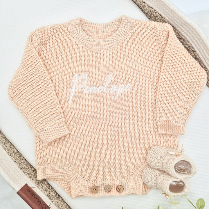 A persoanalised beige oversized long sleeve romper with an emboroidered name on it