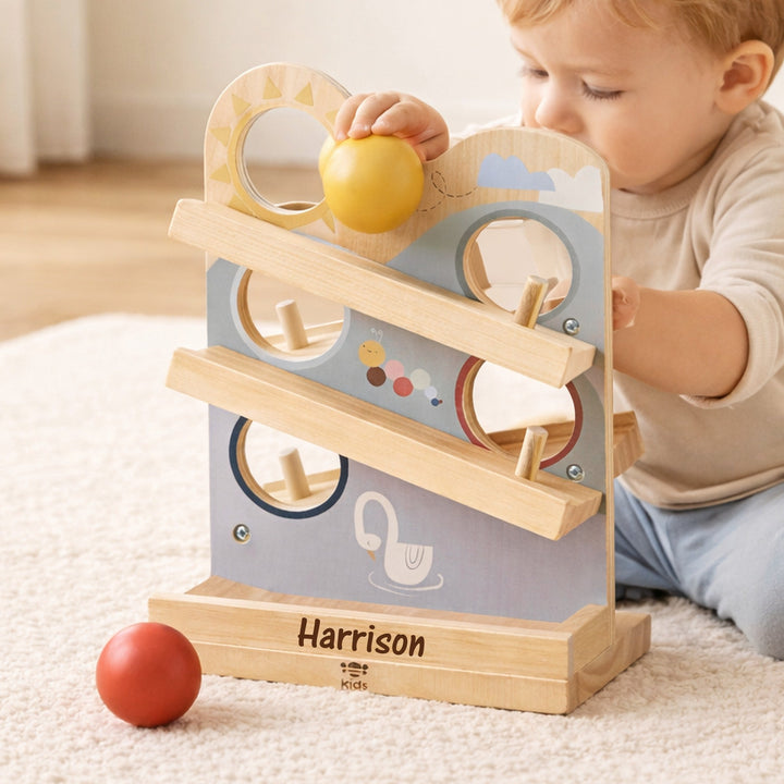Child playing with a wooden toy featuring colorful balls on a light-colored carpet.