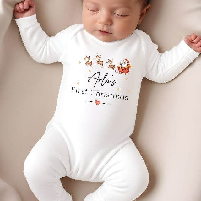 Baby wearing a 'Alo's First Christmas' onesie on a beige surface