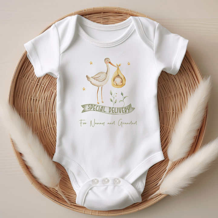 Baby announcement vests that says: 'Special Delivery For Nanny and Grandad' With a white stork carrying a baby in a yellow basket