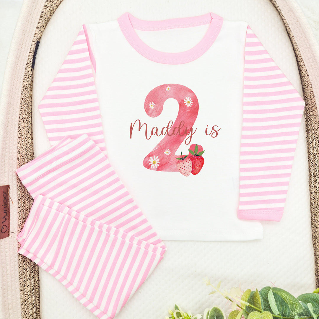 Personalised pink stripe birthday pyjamas saying 'Maddy is 2'. This design features a big pink 2 with strawberry and daisies surronding it