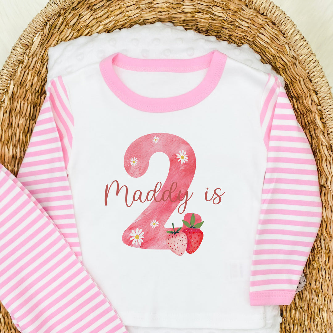 Personalised pink stripe birthday pyjamas saying 'Maddy is 2'. This design features a big pink 2 with strawberry and daisies surronding it