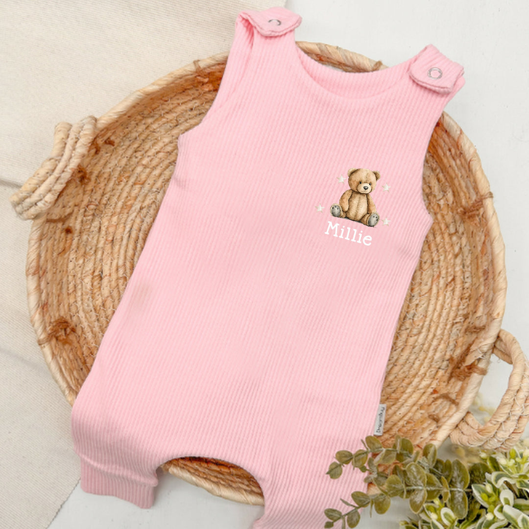 Personalised pink ribbed dungarees that say 'Millie'. This design features a teddy bear surrounded by stars