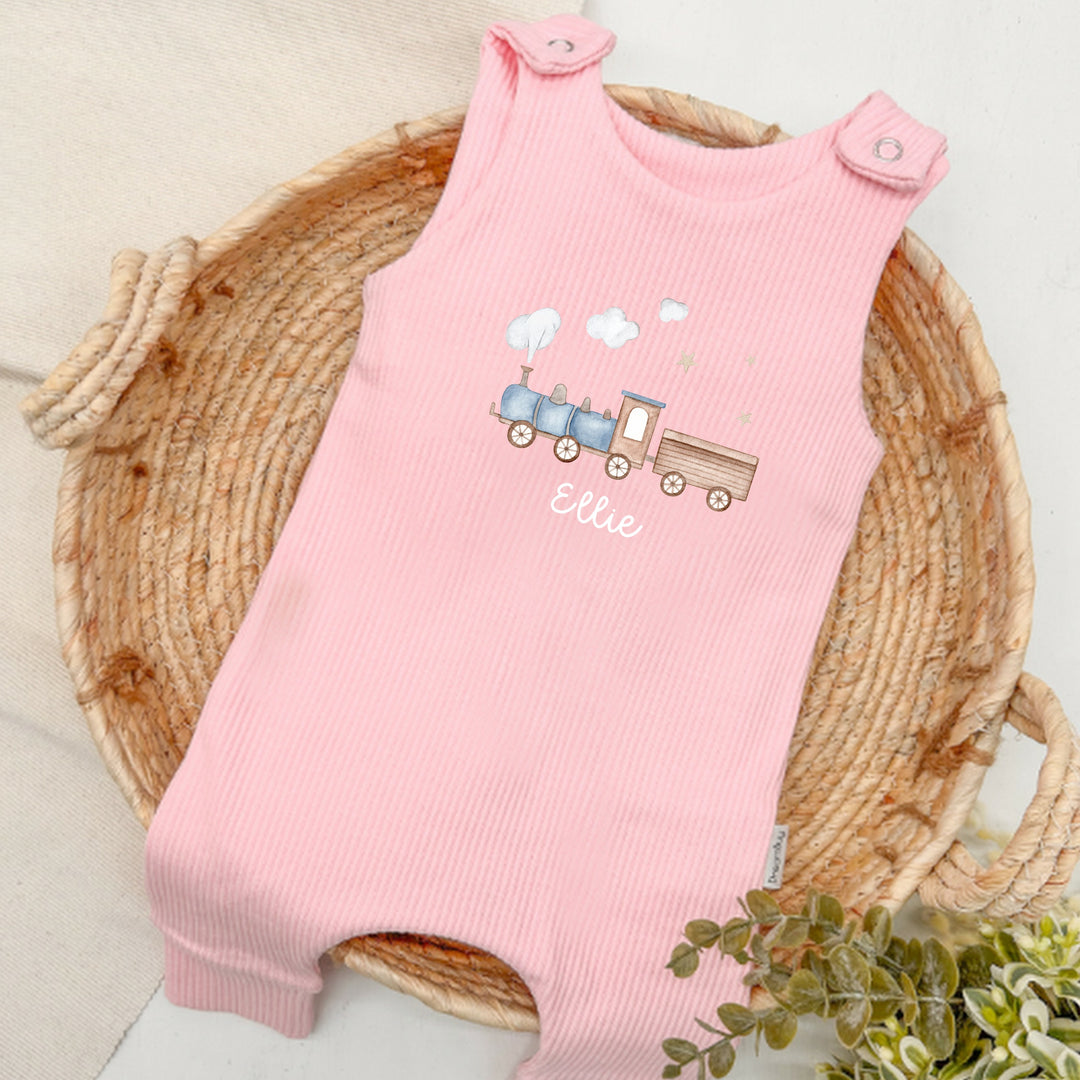 Personalised pink ribbed dungarees that say 'Ellie'. This design features a blue train 