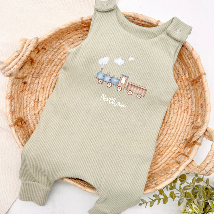 Personalised sage green ribbed dungarees that say 'Nathan'. This design features a blue train 