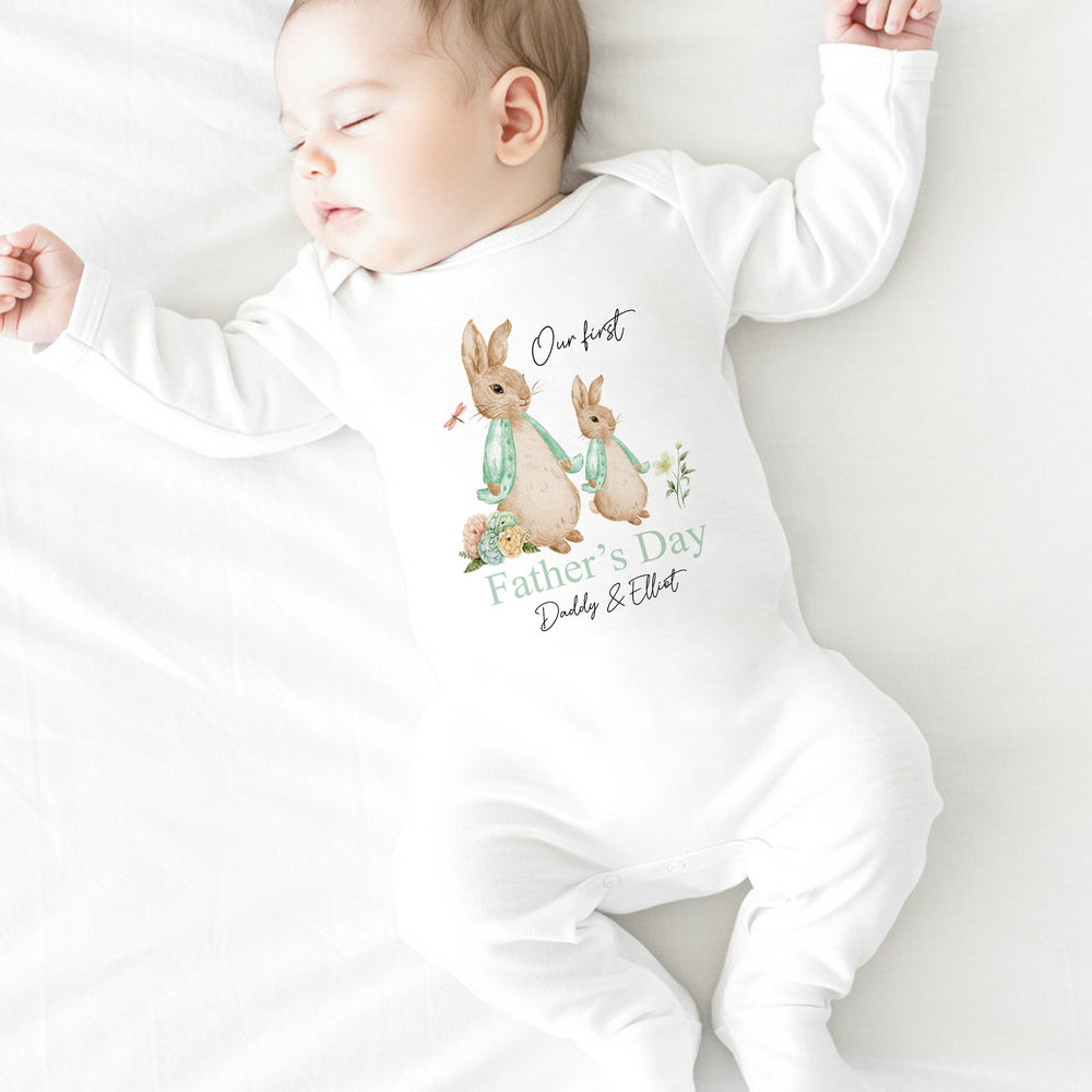 Personalised white Father's Day baby vest that says 'Our First Father's Day Daddy & Elliot'. This design features 2 rabbits wearing sage green jackets