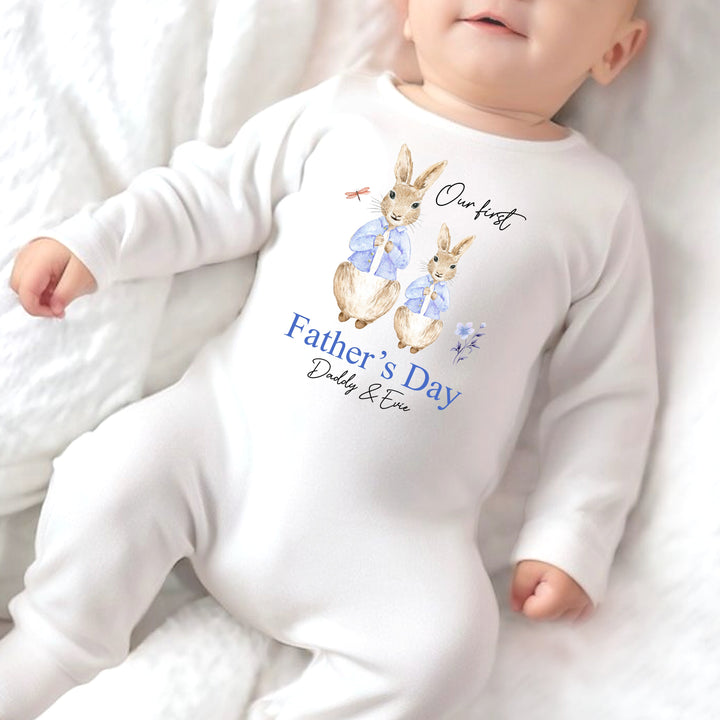 Personalised white Father's Day baby grow/sleepsuit that says 'Our First Father's Day Daddy & Freddie'. This design features 2 rabbits wearing blue jackets