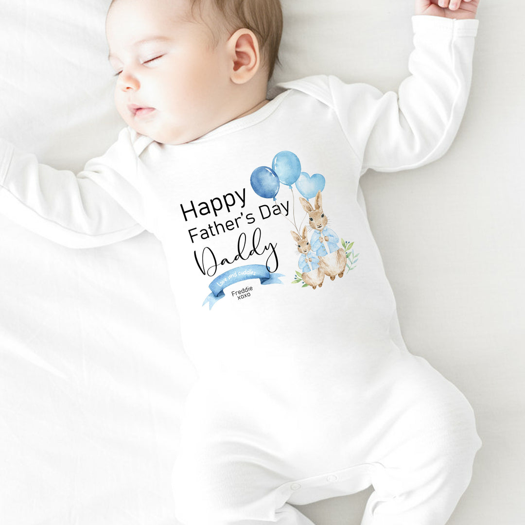 Personalised white Father's Day baby grow/sleepsuit that says 'Happy Father's Day Daddy Love and Cuddles Freddie xoxo'. This design features 2 rabbits wearing blue jackets