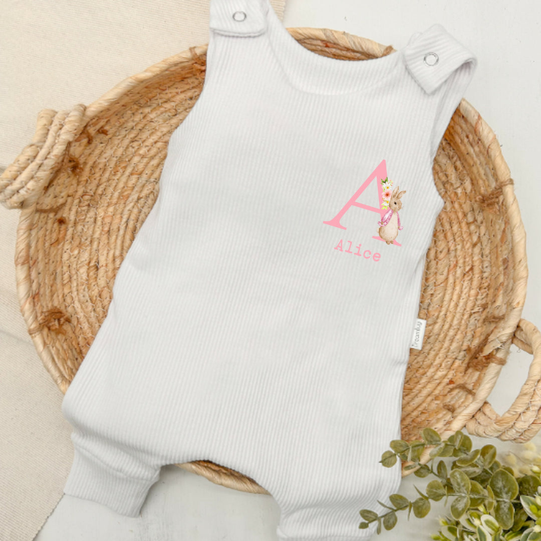 Personalised white ribbed dungarees that say 'Alice'. This design features a rabbit wearing a pink jacket