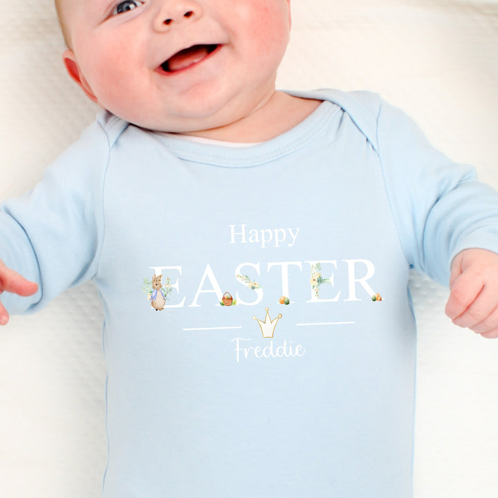 Personalised blue Easter baby grow/sleepsuit that says 'Happy Easter Freddie'. This design features a rabbit wearing a blue jacket with Easter eggs