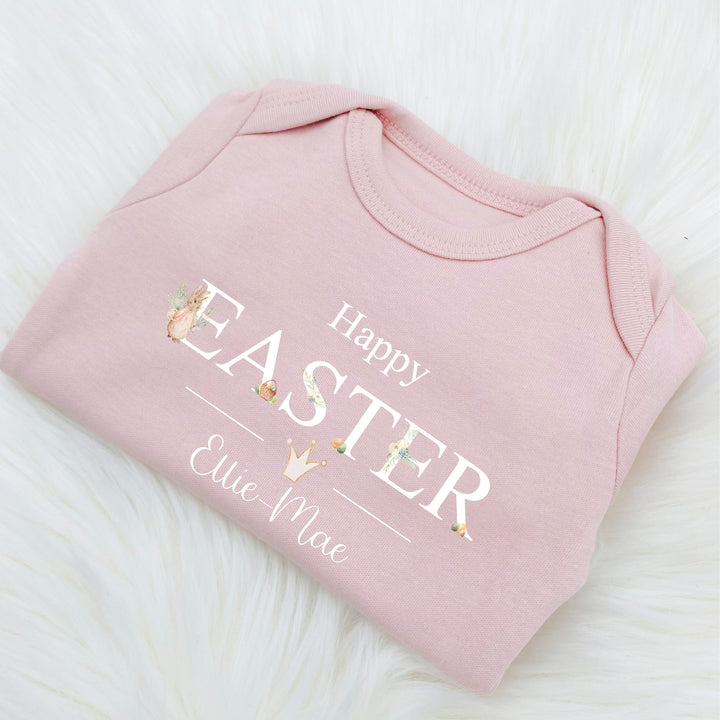 Personalised pink Easter baby grow/sleepsuit that says 'Happy Easter Lilah'. This design features a rabbit wearing a pink jacket