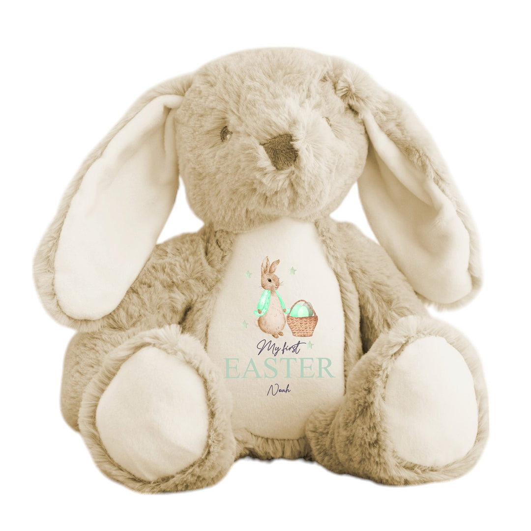 Personalised beige bunny Easter teddy that says 'My First Easter Noah'. This design features a rabbit wearing a green jacket next to a basket full of Easter eggs