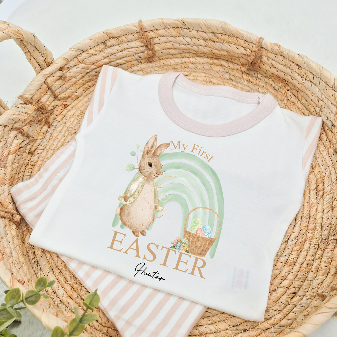 Personalised Beige stripe Easter pyjamas saying 'My First Easter Hunter'. This design features a sage green rainbow and a rabbit wearing a beige jacket