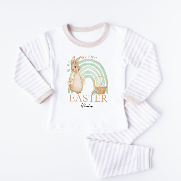 Personalised Beige stripe Easter pyjamas saying 'My First Easter Hunter'. This design features a sage green rainbow and a rabbit wearing a beige jacket