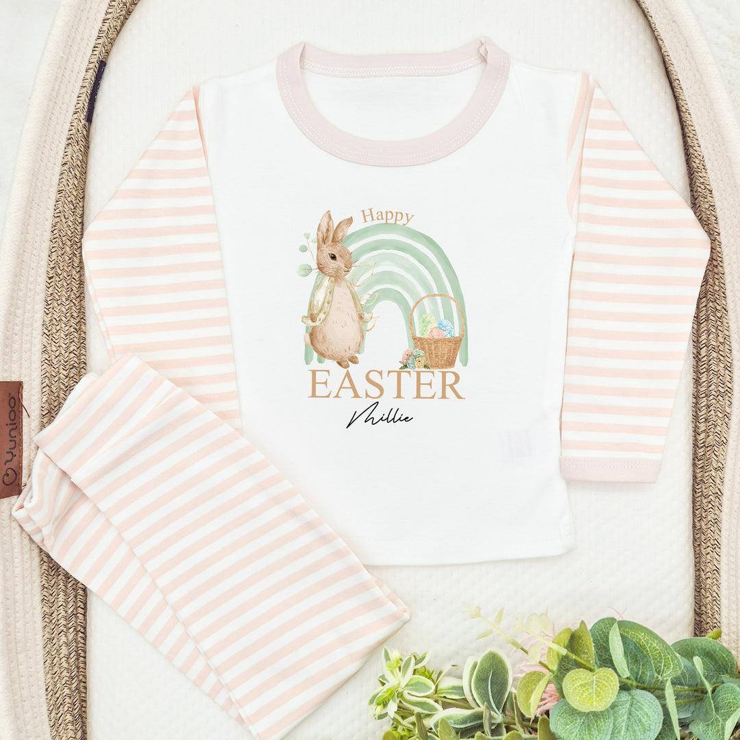 Personalised Beige stripe Easter pyjamas saying 'Happy Easter Millie'. This design features a sage green rainbow and a rabbit wearing a beige jacket