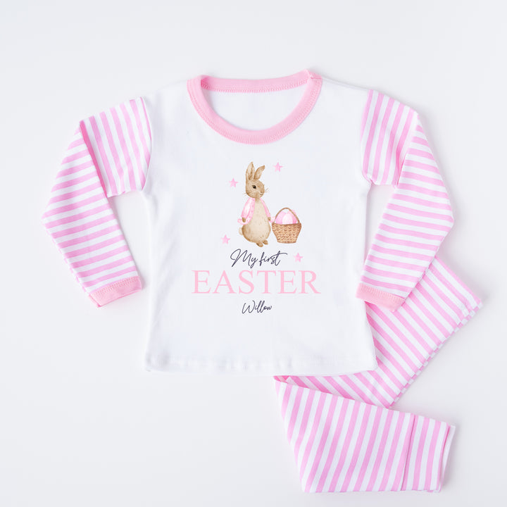 Personalised pink stripe Easter pyjamas saying 'My First Easter Willow'. This design features a rabbit wearing a pink jacket with a basket on pink easter eggs