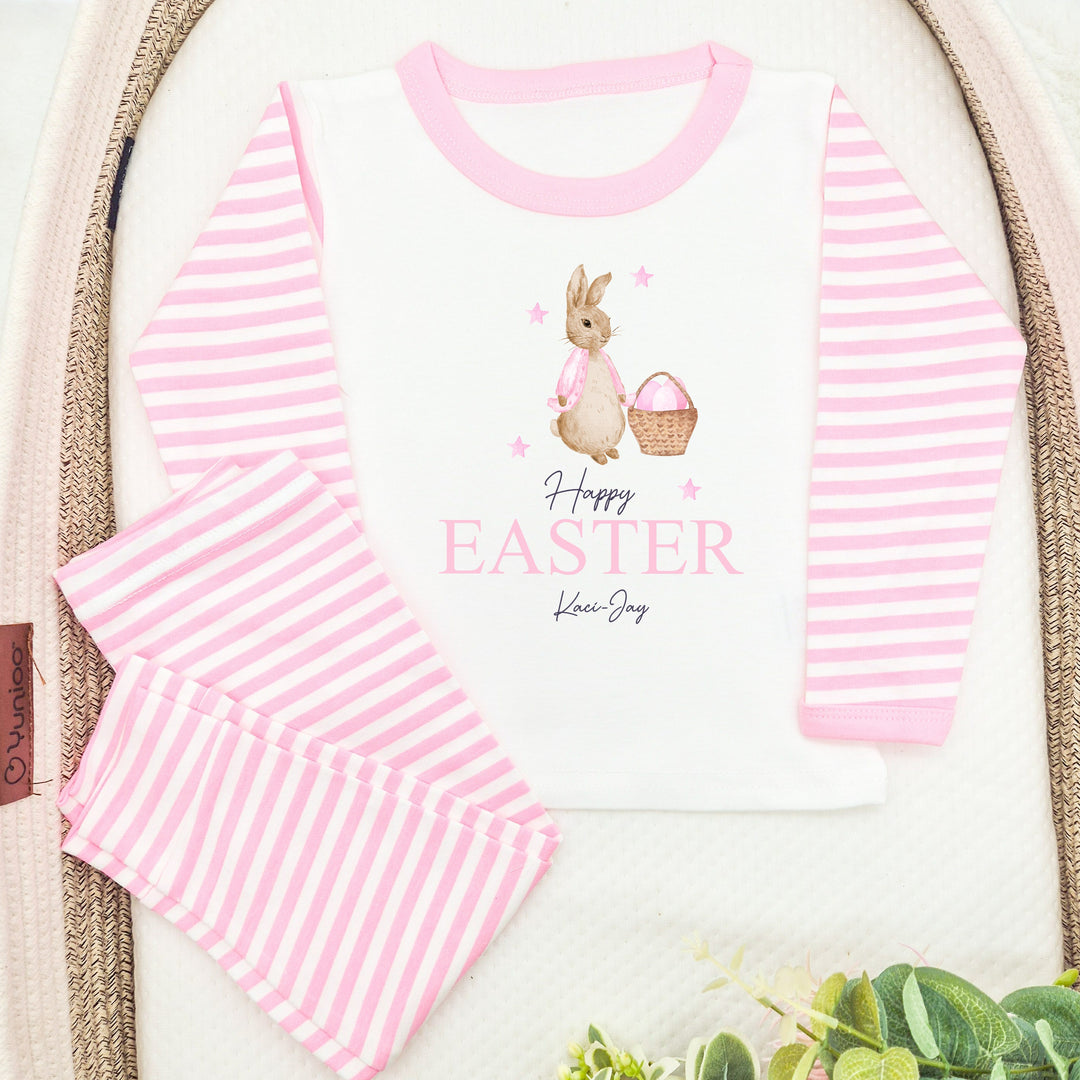 Personalised pink stripe Easter pyjamas saying 'Happy Easter Kaci-Jay'. This design features a rabbit wearing a pink jacket with a basket on pink easter eggs