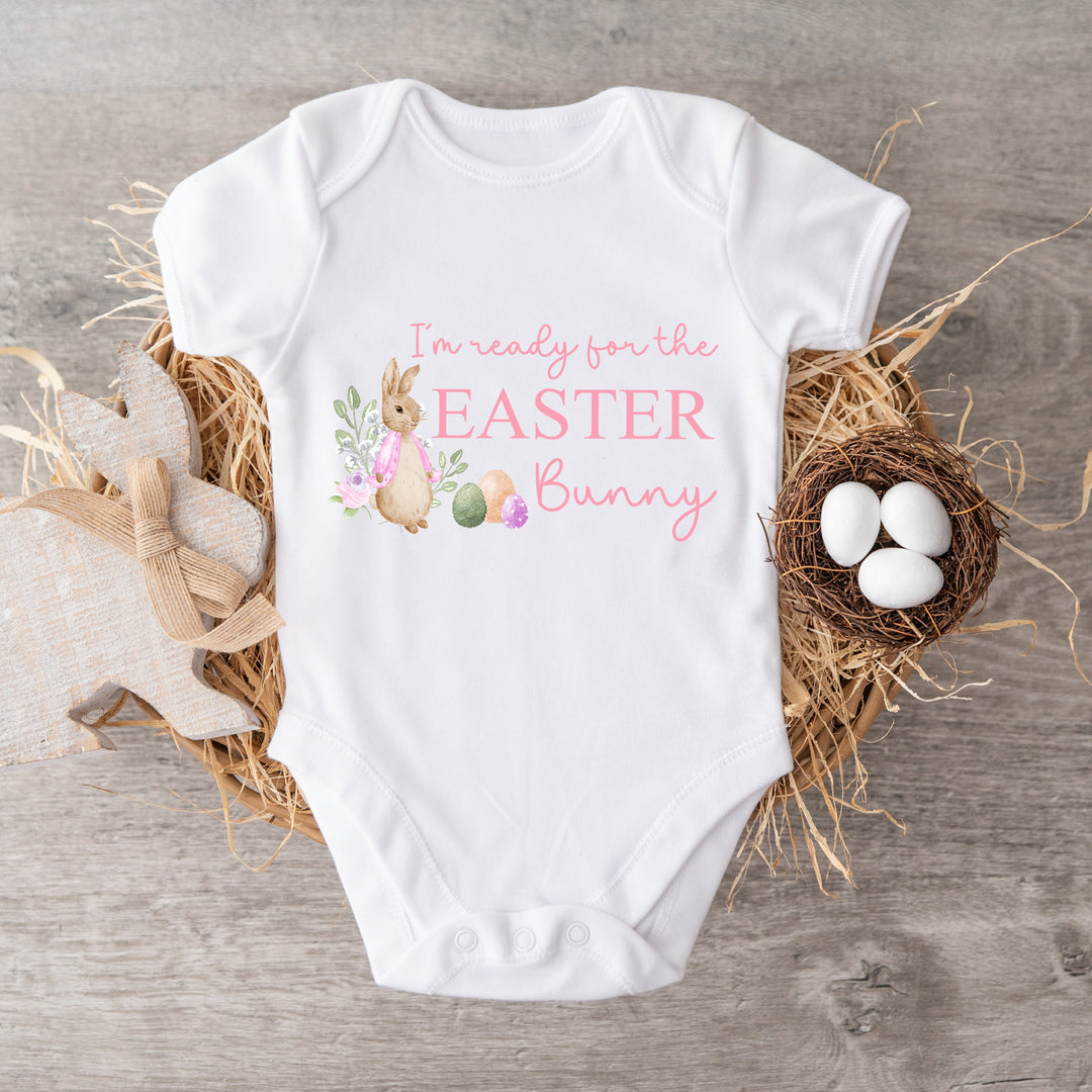 White Easter baby vest that says 'I'm ready for the Easter Bunny'. This design features a rabbit wearing a pink jacket and Easter eggs