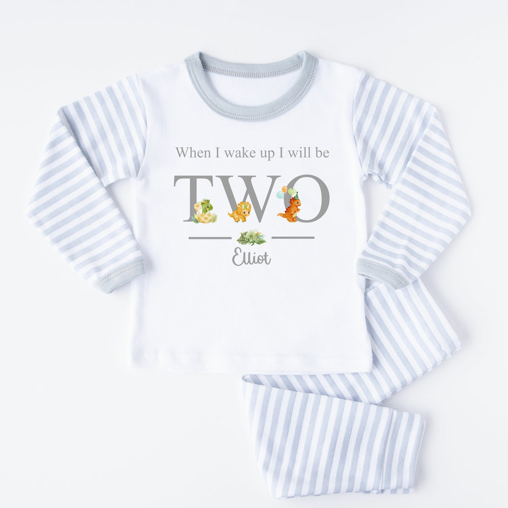 A pair of grey and white stripe children's birthday pyjamas with a dinosaur design saying "When I wake up I will be Two" with the name "Elliot".