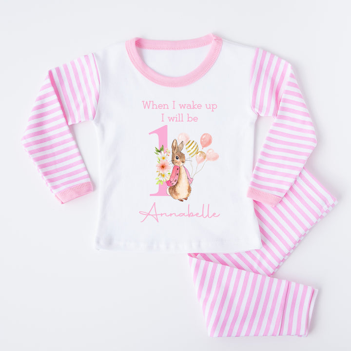 Blue Stripe birthday pyjamas that say 'When I wake up I will be 1 Annabelle'. This design features a rabbit in a pink jacket holding a bunch of balloons