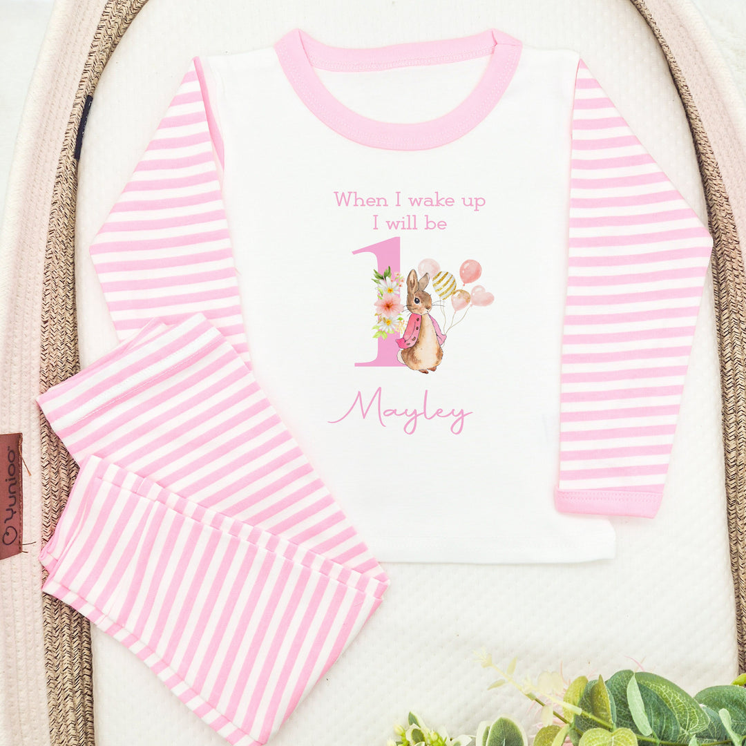 Blue Stripe birthday pyjamas that say 'When I wake up I will be 1 Mayley'. This design features a rabbit in a pink jacket holding a bunch of balloons