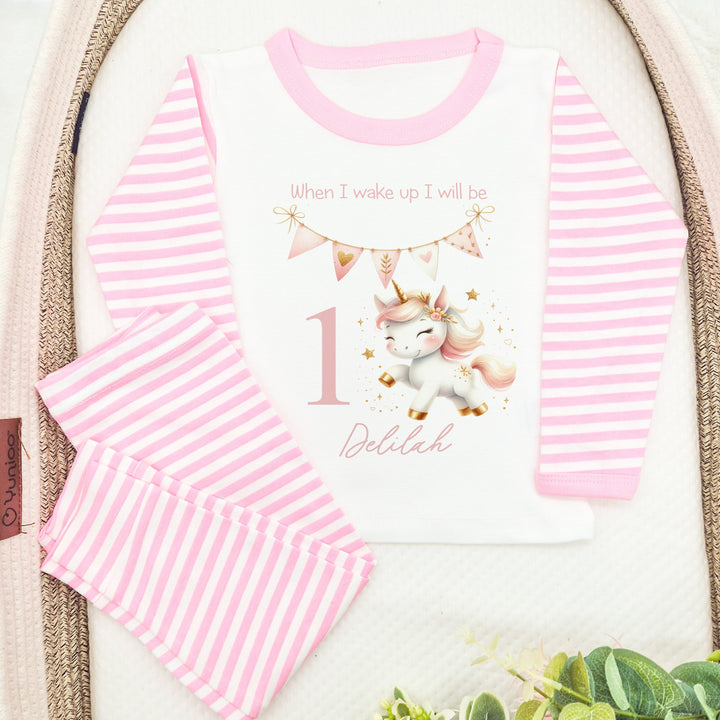 Personalised pink stripe birthday pyjamas that say 'When I wake up I will be 1 Delilah'. This design features a pink pastel unicorn and pink bunting 