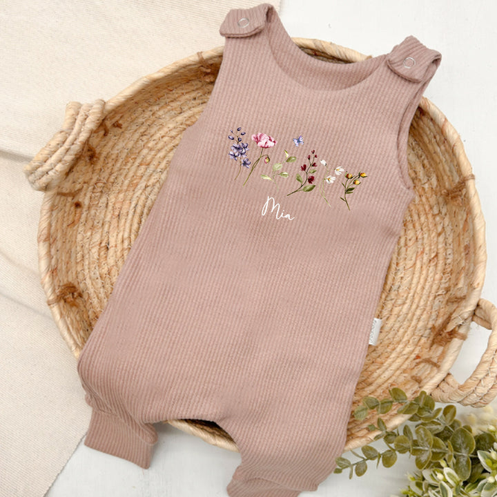 Personalised brown ribbed dungarees that say 'Mia'. This design features a wild flower design