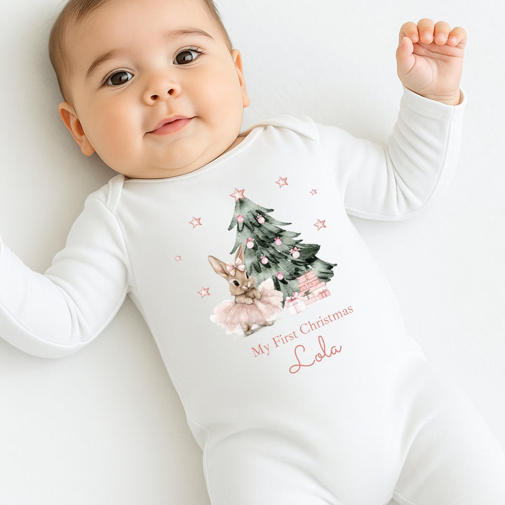 Baby wearing a white onesie with Christmas tree and reindeer design, text 'My First Christmas' and name 'Lola'.