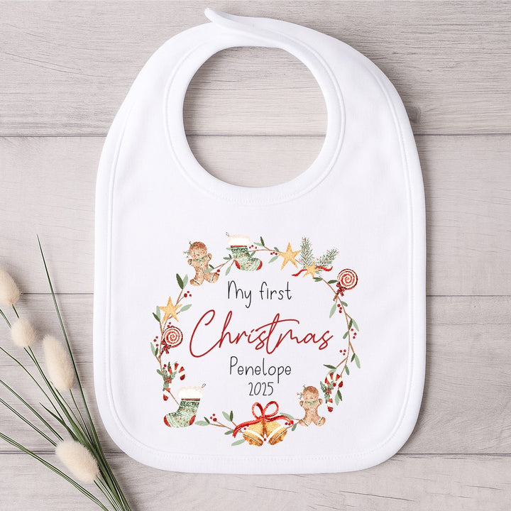 White baby bib with Christmas design and text on a wooden surface