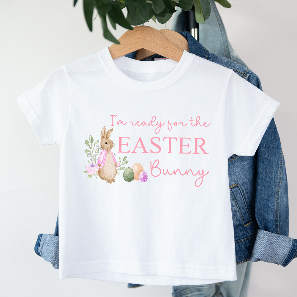 White childrens Easter t-shirt that says 'I'm ready for the Easter Bunny'. This design features a rabbit wearing a pink jacket standing next to some Easter eggs